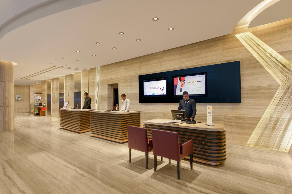 a lobby with a man sitting at a table with a laptop at Novotel Ahmedabad in Ahmedabad