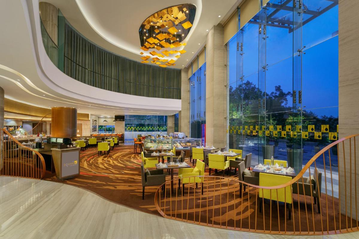 a restaurant with yellow chairs and tables in a building at Novotel Ahmedabad in Ahmedabad