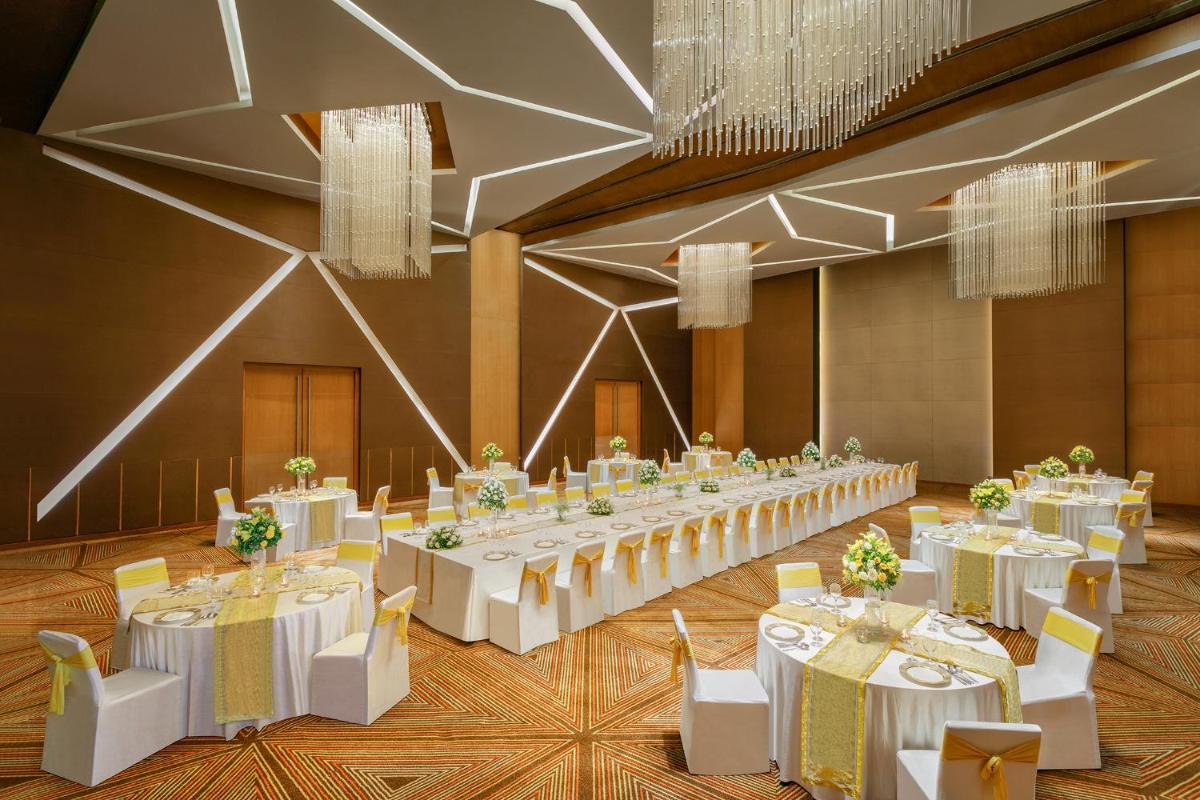 a banquet hall with white tables and chairs and chandeliers at Novotel Ahmedabad in Ahmedabad +144 photos