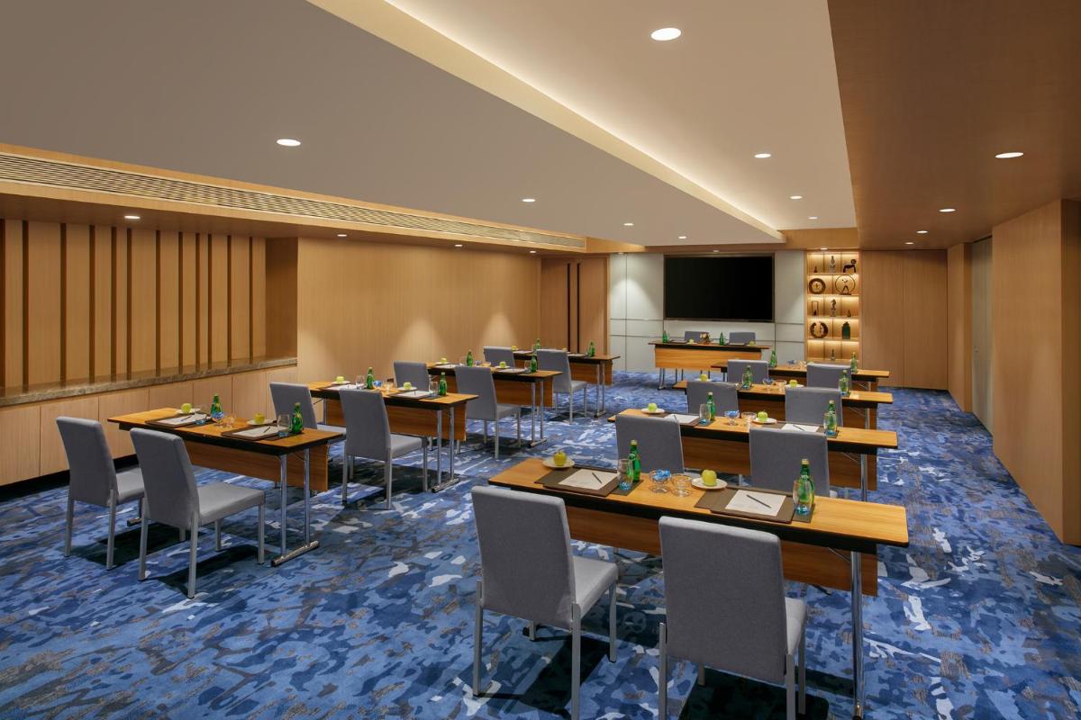 a conference room with tables and chairs and a screen at Novotel Ahmedabad in Ahmedabad