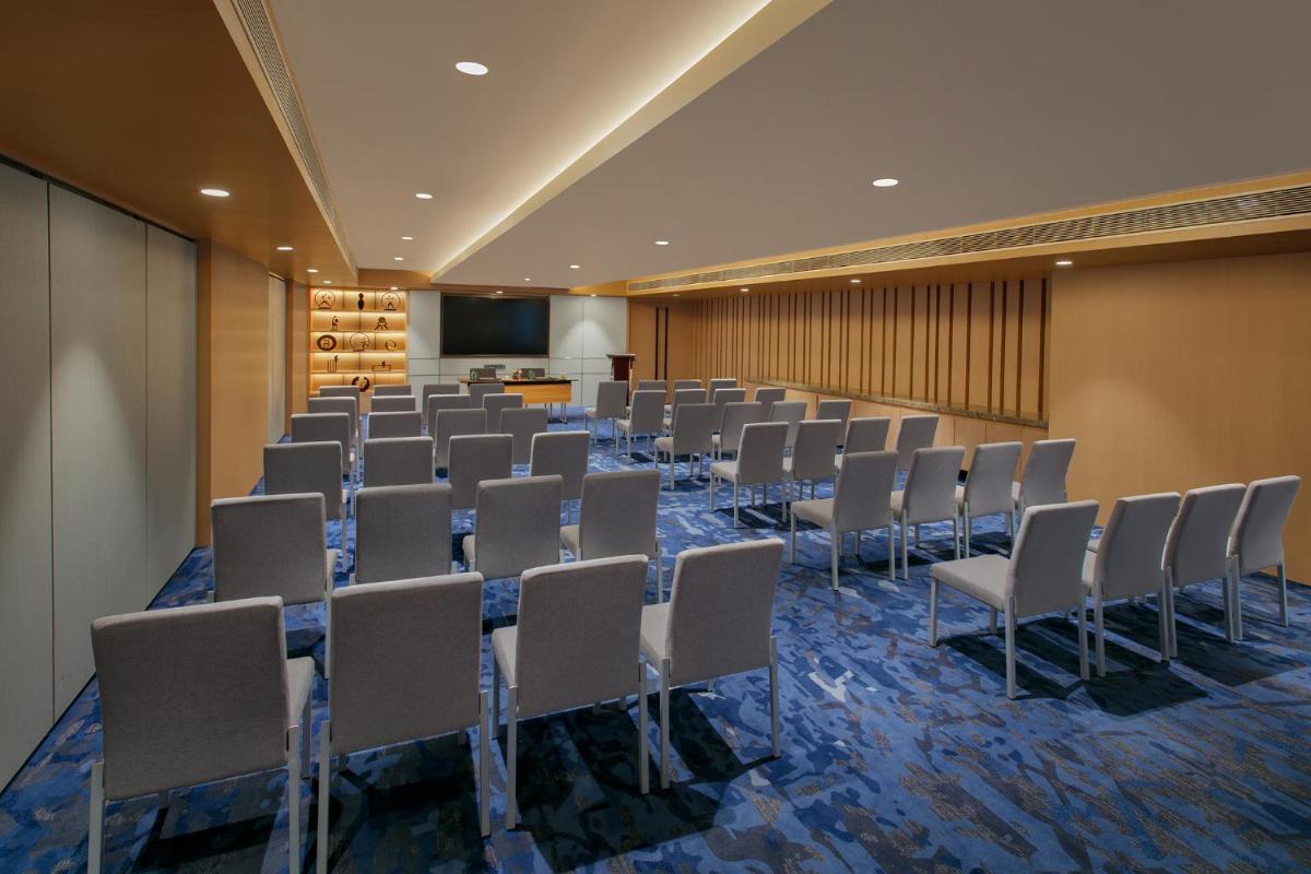 a conference room with rows of chairs and a screen at Novotel Ahmedabad in Ahmedabad