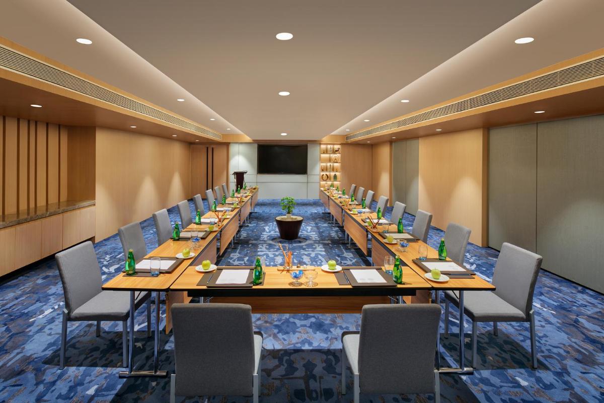 a large conference room with long tables and chairs at Novotel Ahmedabad in Ahmedabad