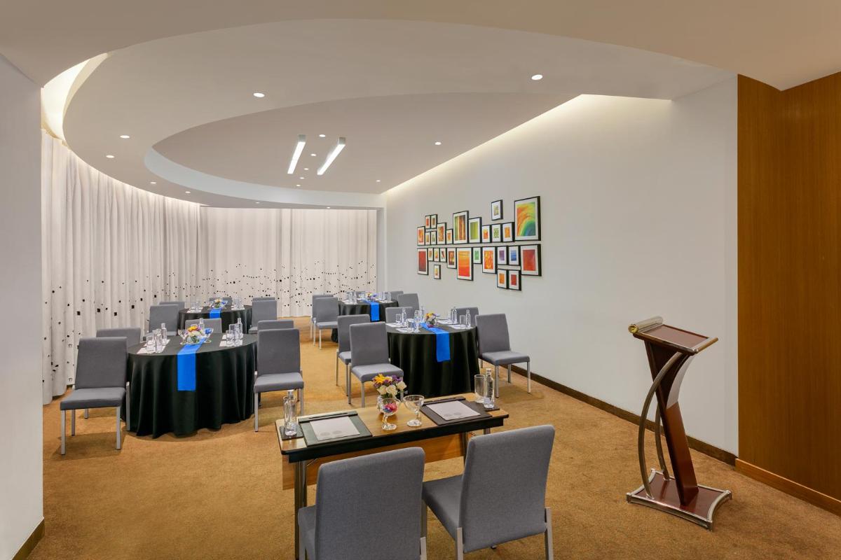 a conference room with tables and chairs and a podium at Novotel Ahmedabad in Ahmedabad