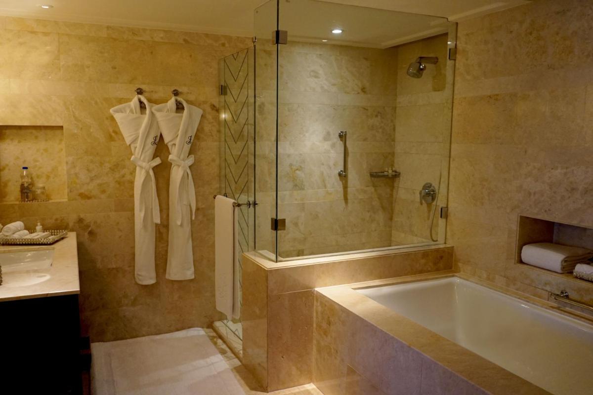 a bathroom with a shower and a tub and a sink at The Leela Palace Udaipur in Udaipur