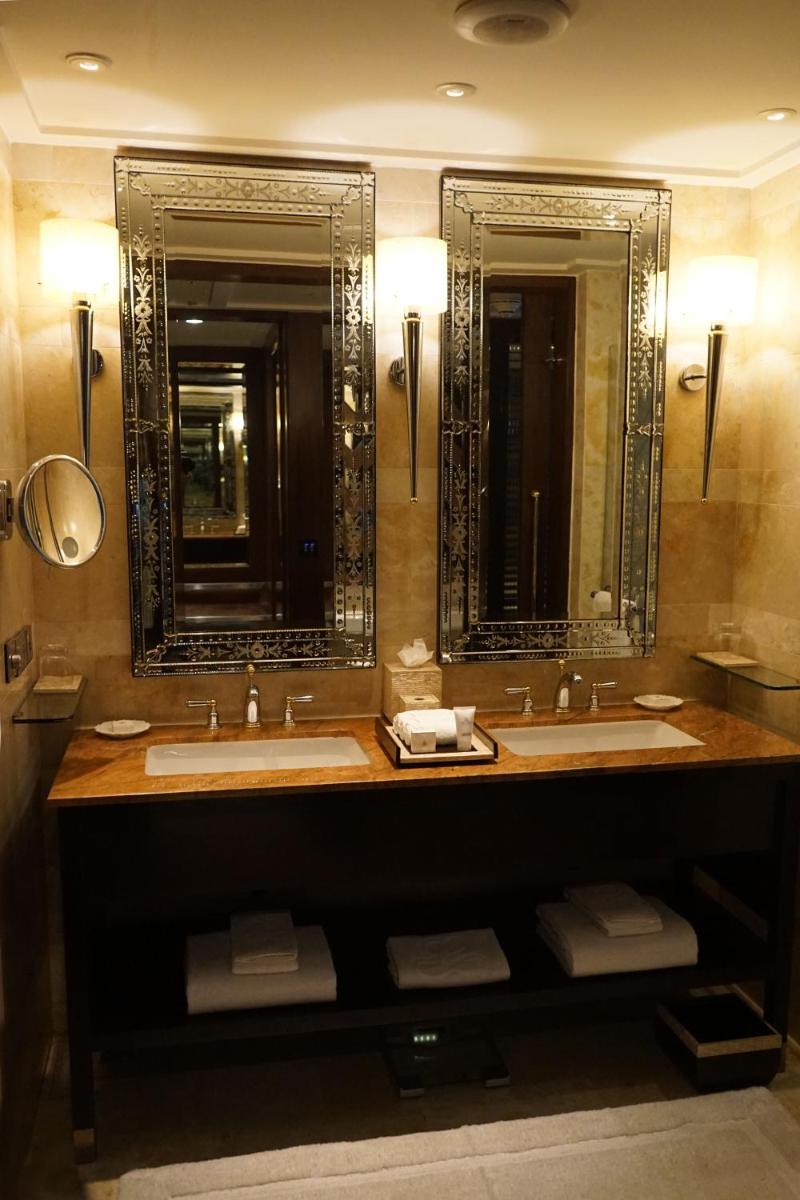 a bathroom with two sinks and two mirrors at The Leela Palace Udaipur in Udaipur