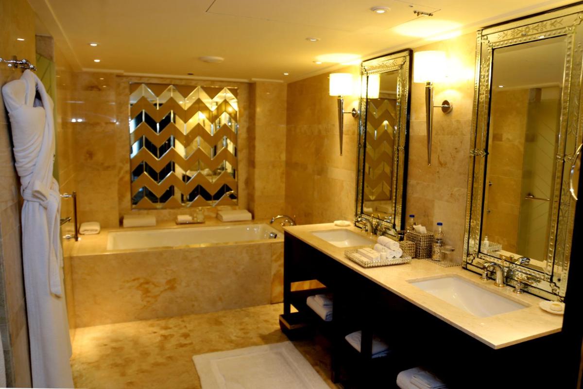 a bathroom with two sinks and a bath tub and a tubermott at The Leela Palace Udaipur in Udaipur