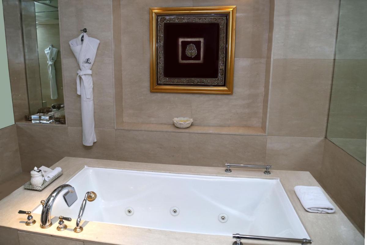 a bath tub in a bathroom with a sink at The Leela Palace Udaipur in Udaipur