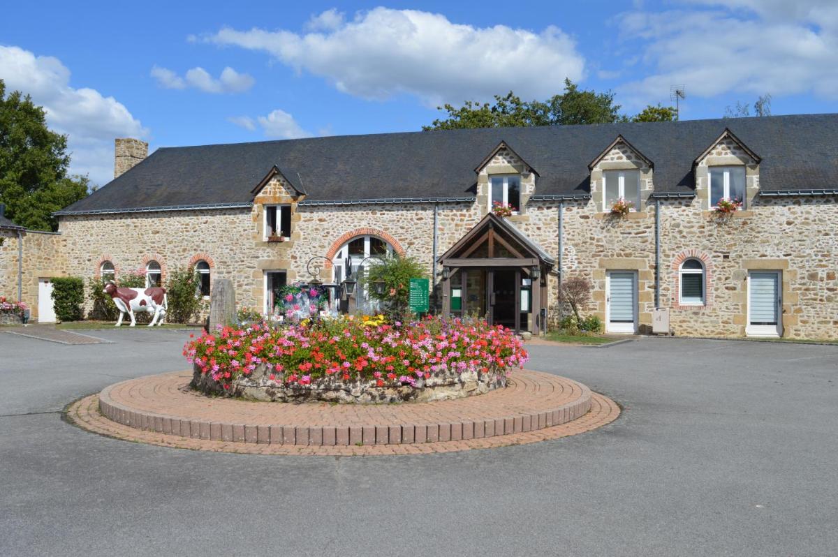 un grand bâtiment en briques avec des fleurs devant dans l'établissement Logis Hôtel Restaurant Relais Du Gué De Selle, à Évron