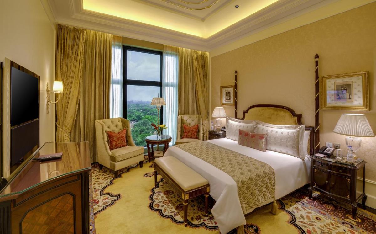 a bedroom with a large bed and a large window at The Leela Palace New Delhi in New Delhi a bedroom with a large bed and a large window at The Leela Palace New Delhi in New Delhi