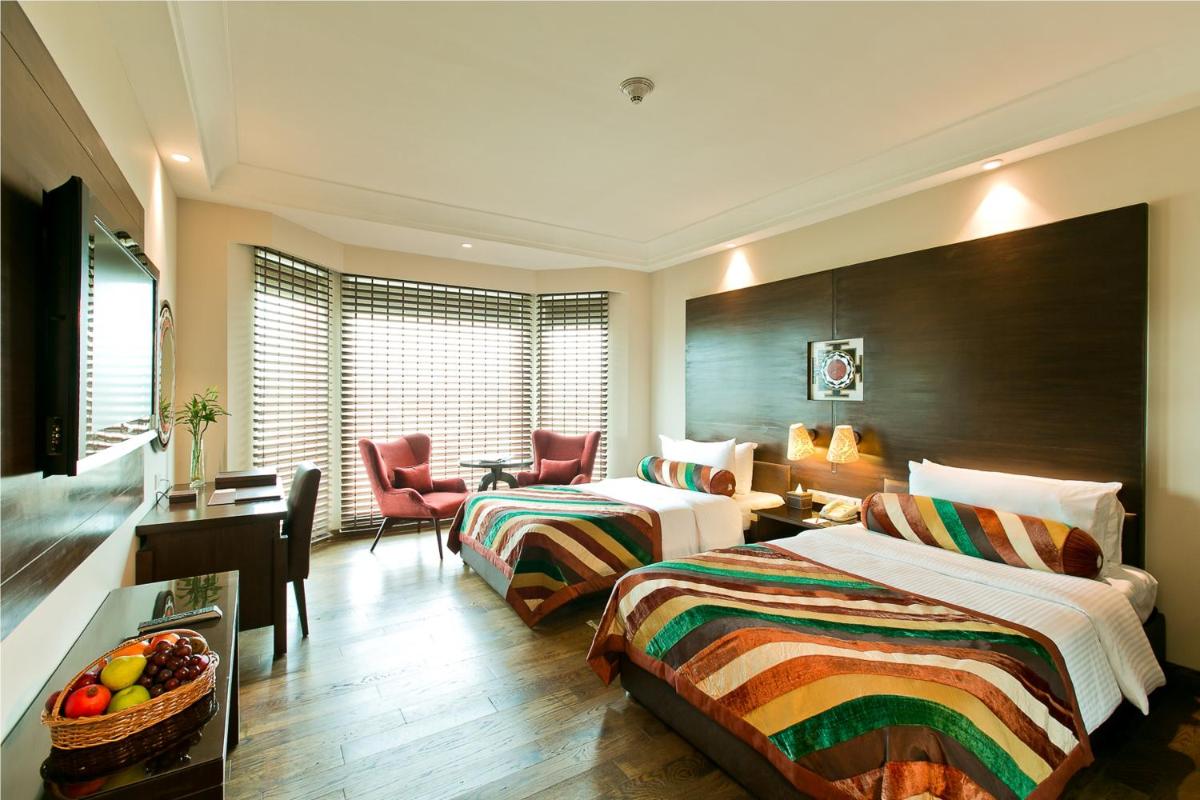 a hotel room with two beds and a desk at The Lalit Jaipur in Jaipur