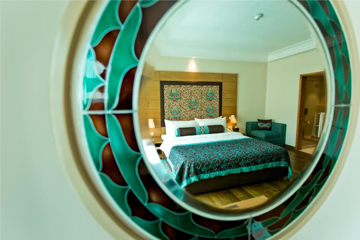 a bedroom with a bed and a mirror at The Lalit Jaipur in Jaipur