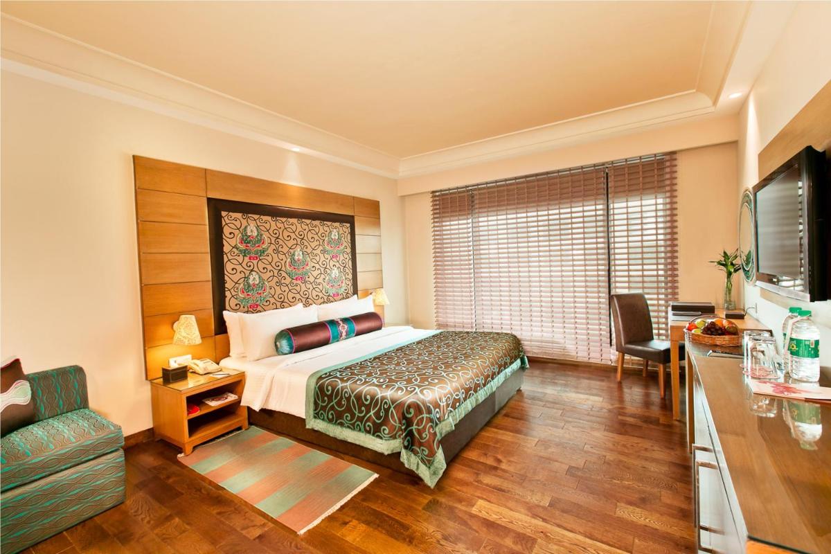 a hotel room with a bed and a television at The Lalit Jaipur in Jaipur a hotel room with a bed and a television at The Lalit Jaipur in Jaipur