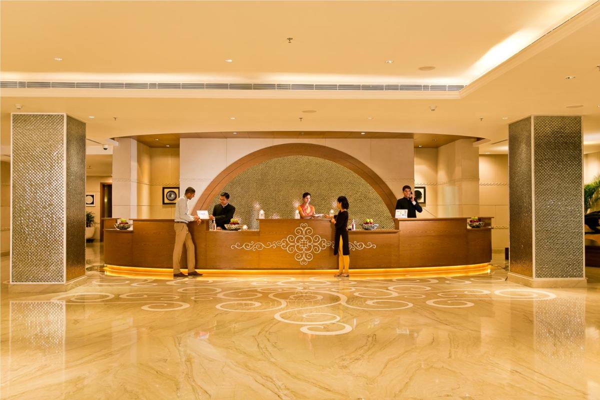a lobby of a hotel with people standing at a counter at The Lalit Jaipur in Jaipur