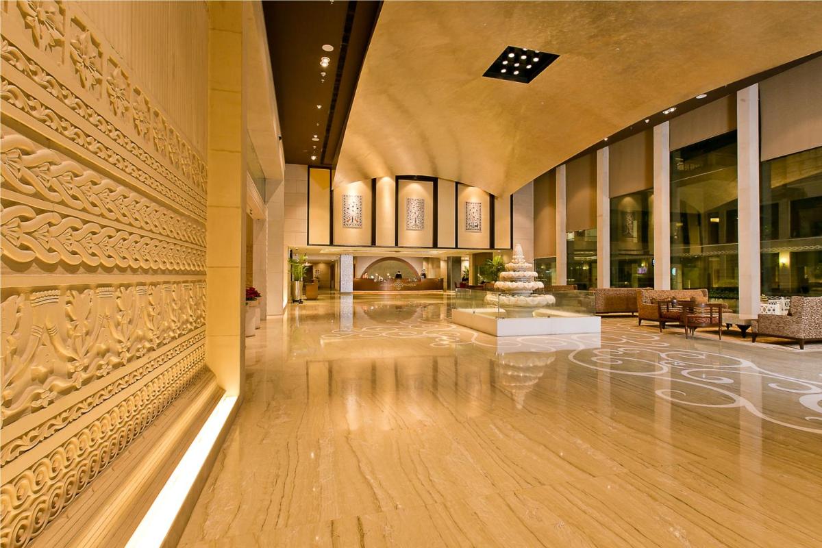 a lobby with a fountain in the middle of a building at The Lalit Jaipur in Jaipur