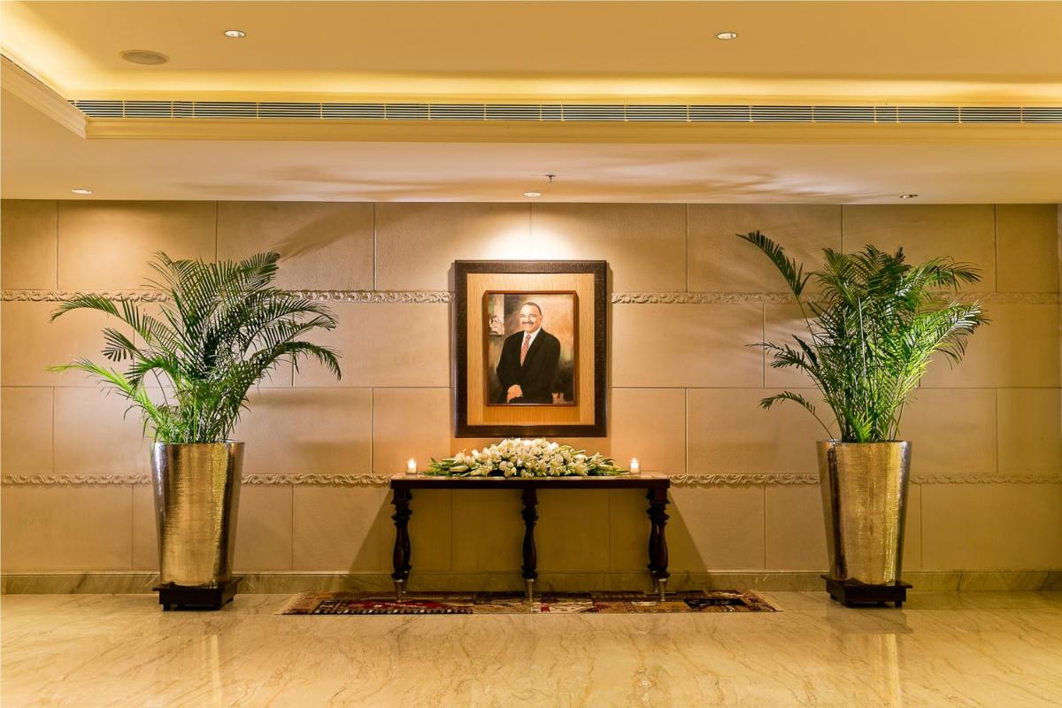 a lobby with two plants and a picture of a man at The Lalit Jaipur in Jaipur