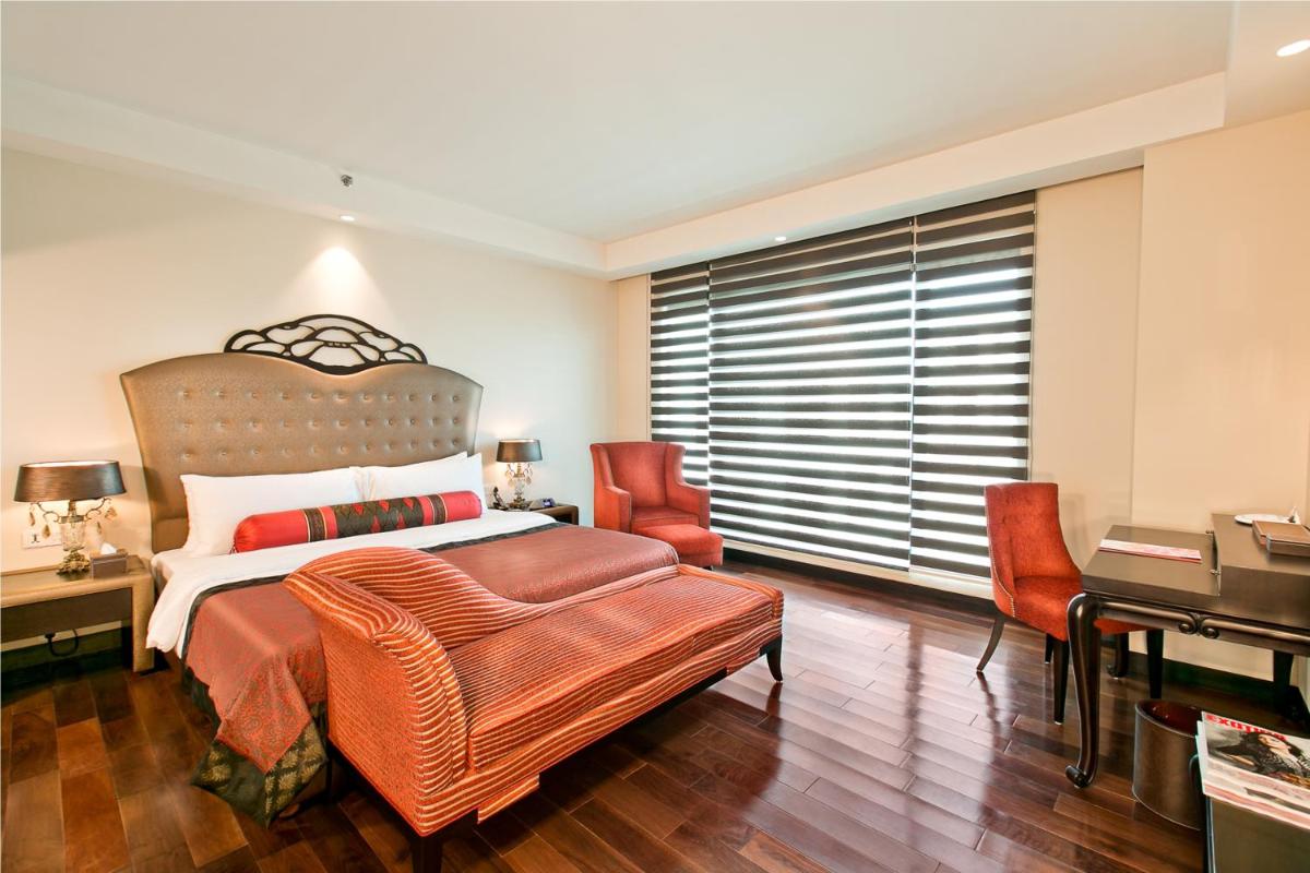 a bedroom with a bed and a desk and a piano at The Lalit Jaipur in Jaipur
