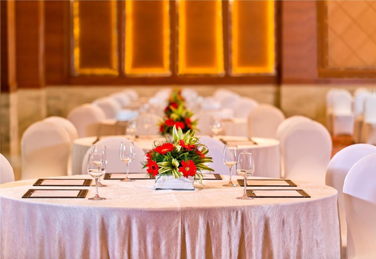 a long table with glasses and flowers on it at The Lalit Jaipur in Jaipur
