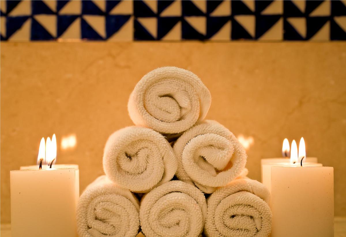 a stack of towels on a table with two candles at The Lalit Jaipur in Jaipur