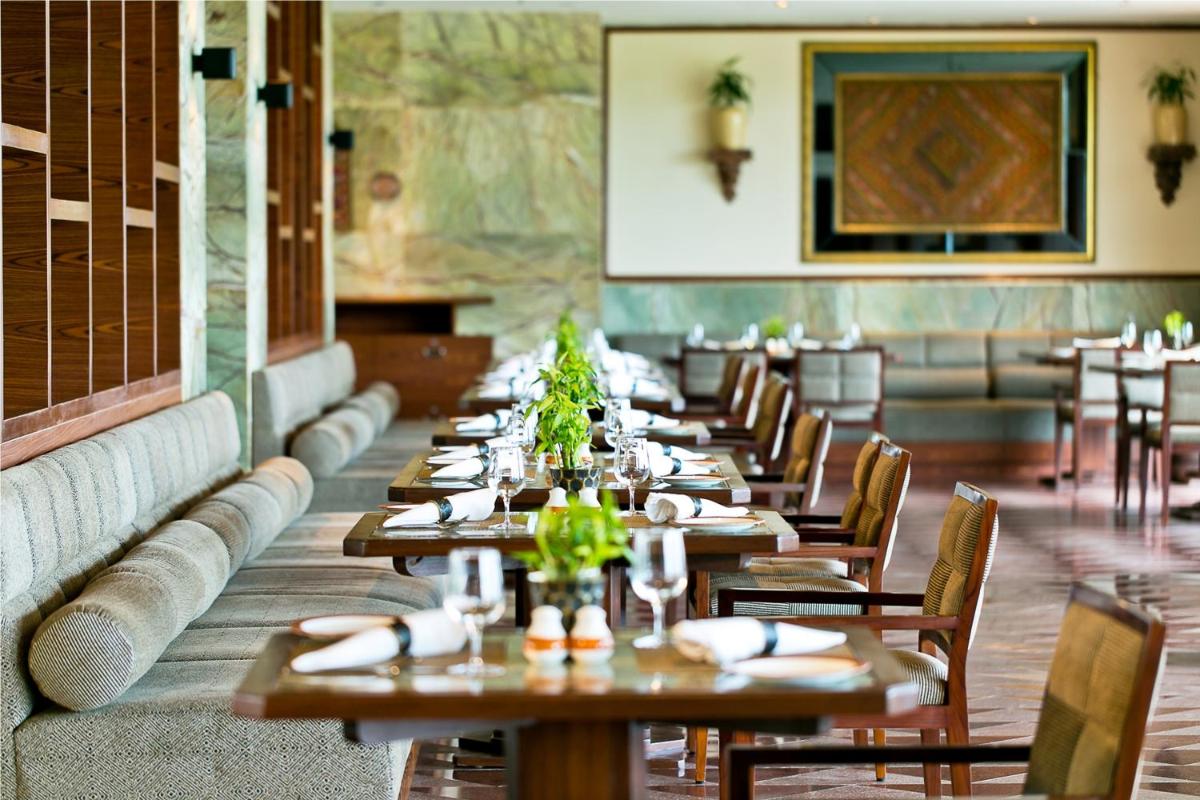 a row of tables in a restaurant with chairs at The Lalit Jaipur in Jaipur