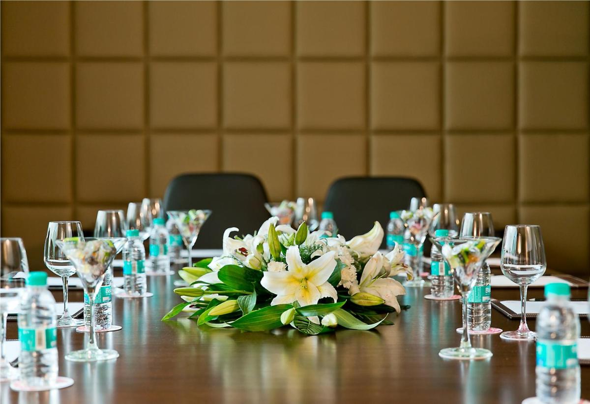 a table with a bouquet of flowers and wine glasses at The Lalit Jaipur in Jaipur
