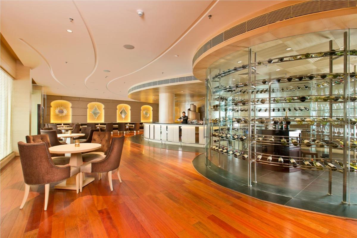 a restaurant with a table and chairs and a wine cellar at The Lalit Jaipur in Jaipur