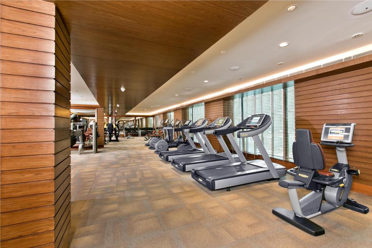 a gym with a row of treadms and cardio machines at The Lalit Jaipur in Jaipur