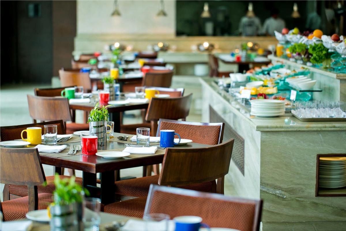 a dining room with tables and chairs with plates and dishes at The Lalit Jaipur in Jaipur