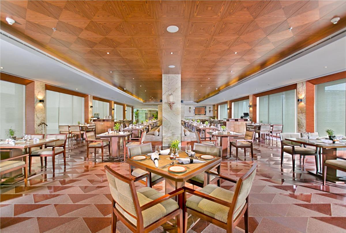 a restaurant with tables and chairs in a room at The Lalit Jaipur in Jaipur a restaurant with tables and chairs in a room at The Lalit Jaipur in Jaipur