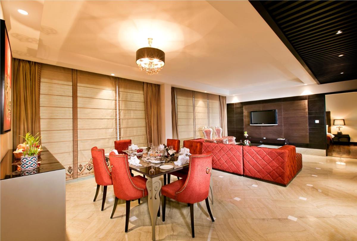 a dining room with a table and red chairs at The Lalit Jaipur in Jaipur