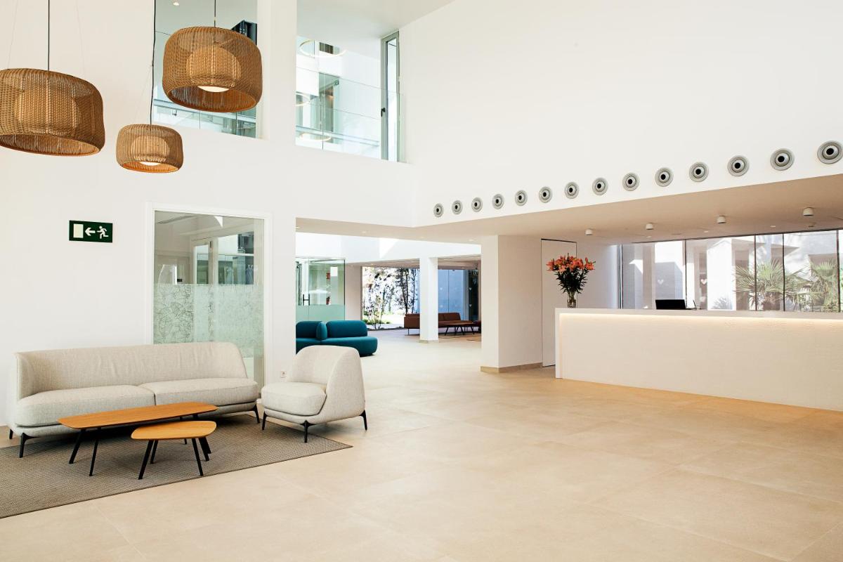 Un vestíbulo con un sofá y sillas y una mesa. en Diamant Hotel & Aparthotel, en Cala Ratjada