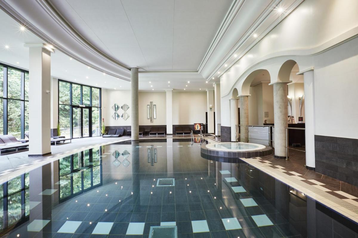 une piscine au milieu d'un immeuble dans l'établissement Hotel & Spa Le Pavillon, à Charbonnières-les-Bains