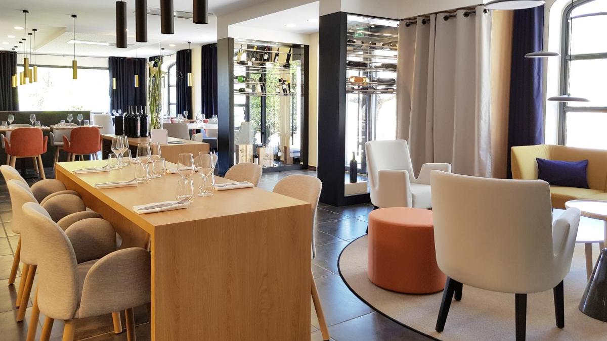 un restaurant avec des tables et des chaises blanches ainsi qu'une salle à manger dans l'établissement Le Domaine Du Colombier, à Malataverne
