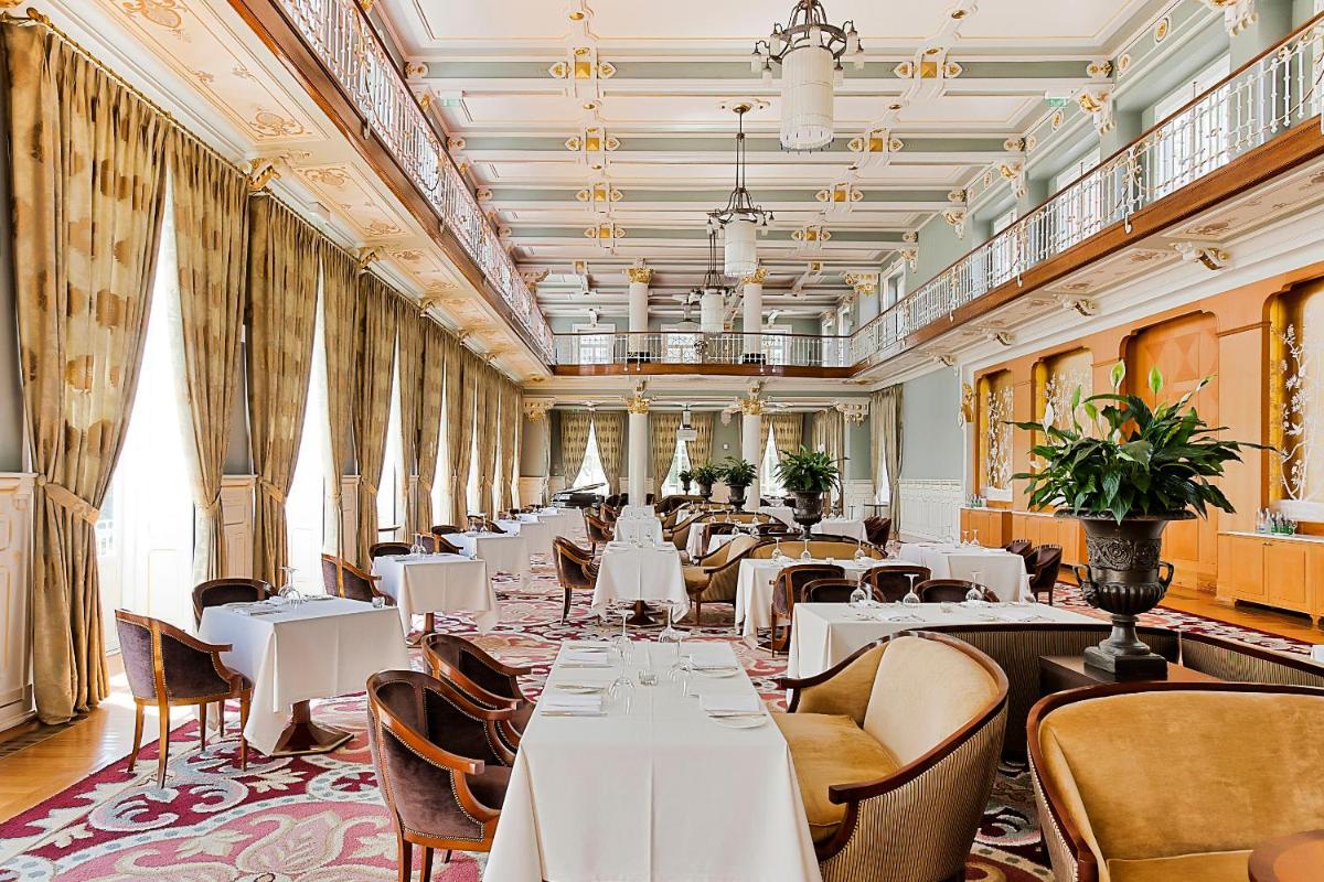 um restaurante com mesas, cadeiras e janelas brancas em Vidago Palace em Vidago
