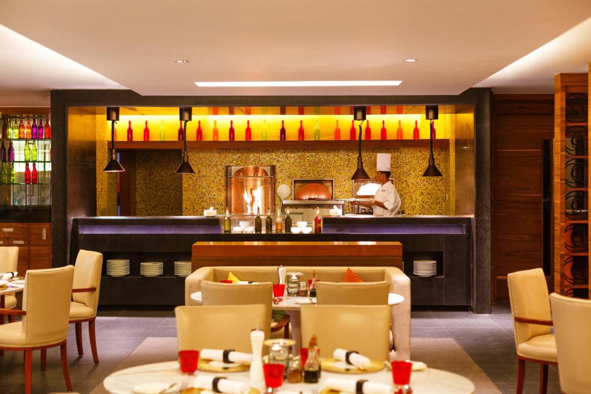 a restaurant with tables and chairs and a chef in the kitchen at Crowne Plaza Ahmedabad City Centre by IHG in Ahmedabad