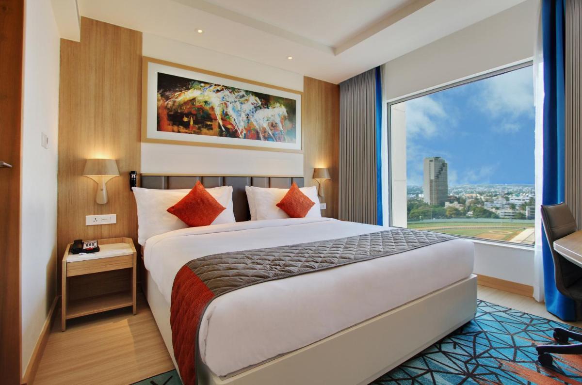 a hotel room with a bed and a large window at Holiday Inn Bengaluru Racecourse by IHG in Bengaluru a hotel room with a bed and a large window at Holiday Inn Bengaluru Racecourse by IHG in Bengaluru