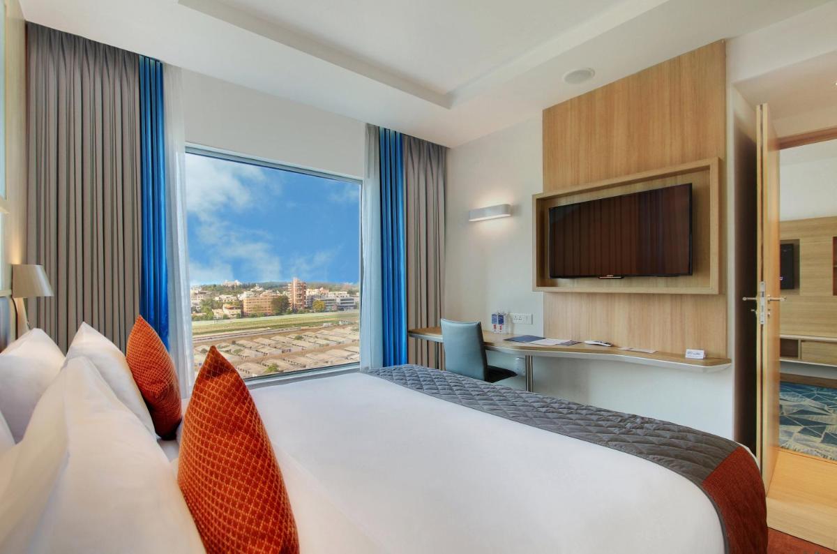 a hotel room with a large bed with a large window at Holiday Inn Bengaluru Racecourse by IHG in Bengaluru a hotel room with a large bed with a large window at Holiday Inn Bengaluru Racecourse by IHG in Bengaluru