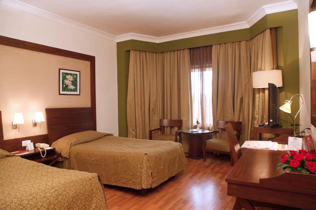 a hotel room with two beds and a desk at The Retreat Hotel & Convention Centre in Mumbai