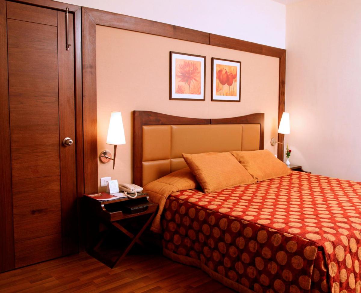 a hotel room with a bed and a table with a phone at The Retreat Hotel & Convention Centre in Mumbai