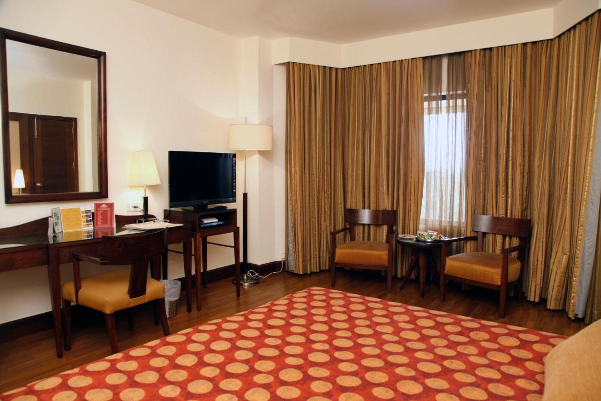 a hotel room with a desk and a large room at The Retreat Hotel & Convention Centre in Mumbai