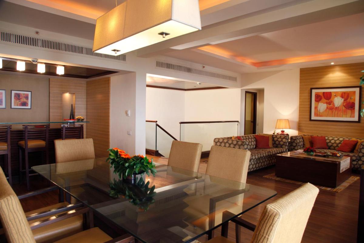 a dining room and living room with a glass table at The Retreat Hotel & Convention Centre in Mumbai