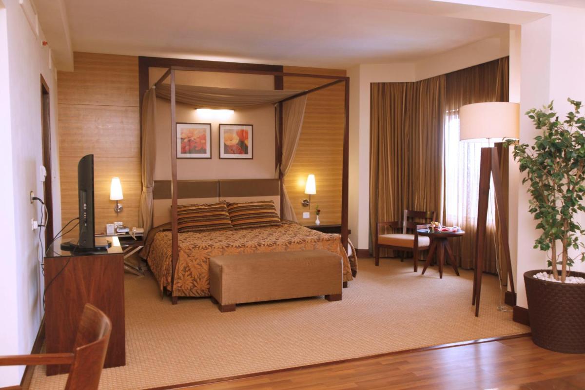 a hotel room with a bed and a television at The Retreat Hotel & Convention Centre in Mumbai a hotel room with a bed and a television at The Retreat Hotel & Convention Centre in Mumbai