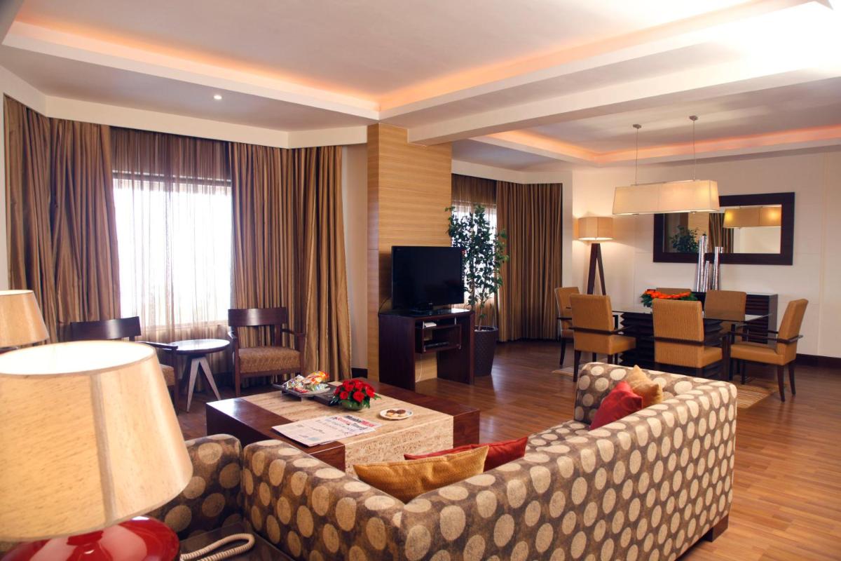 a living room with a couch and a dining room at The Retreat Hotel & Convention Centre in Mumbai a living room with a couch and a dining room at The Retreat Hotel & Convention Centre in Mumbai