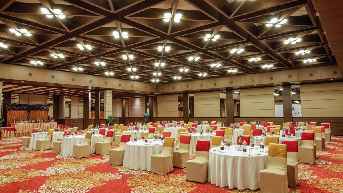 a banquet hall with white tables and chairs at Sterlings Mac Hotel in Bengaluru
