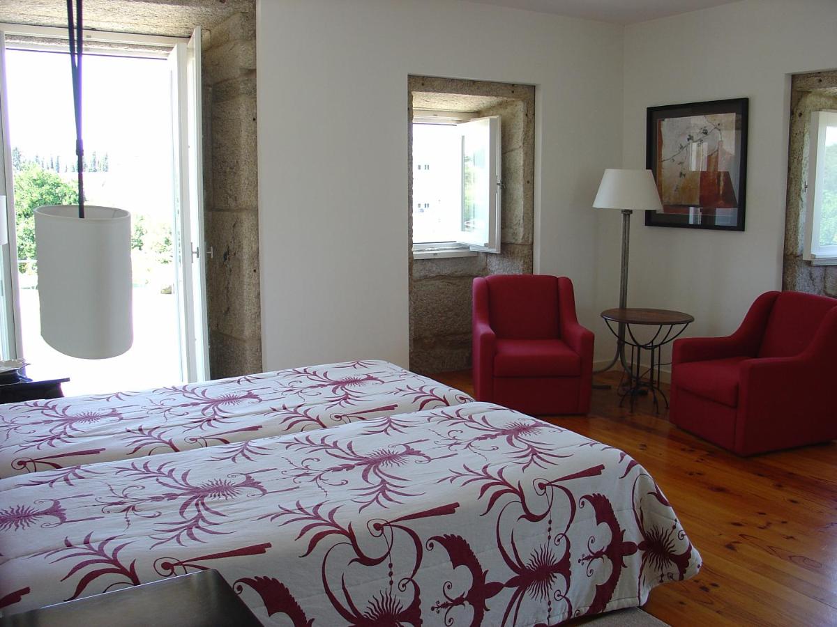 um quarto com uma cama e duas cadeiras vermelhas em Hotel Convento dos Capuchos em Monção