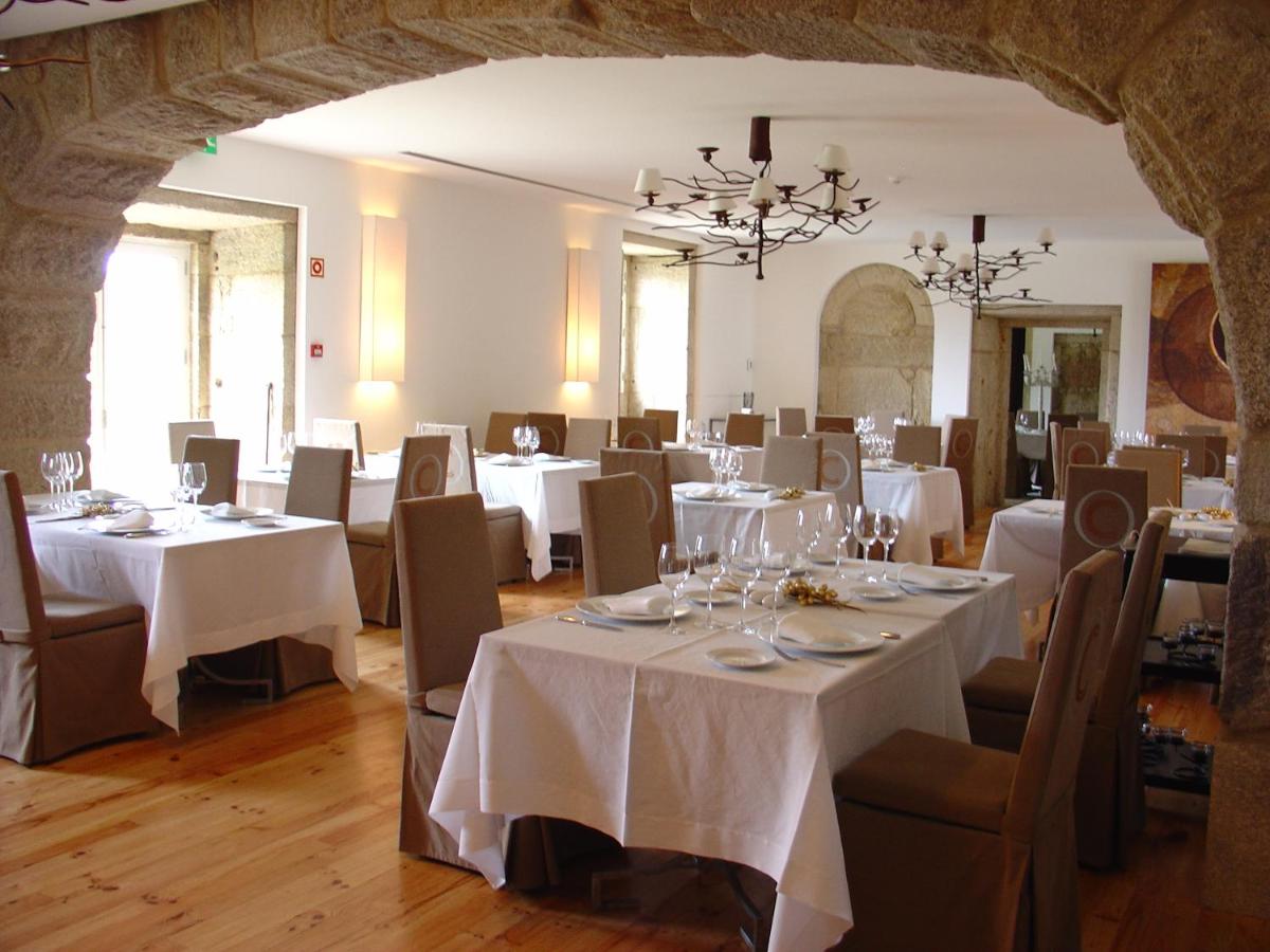uma sala de jantar com mesas e cadeiras brancas em Hotel Convento dos Capuchos em Monção