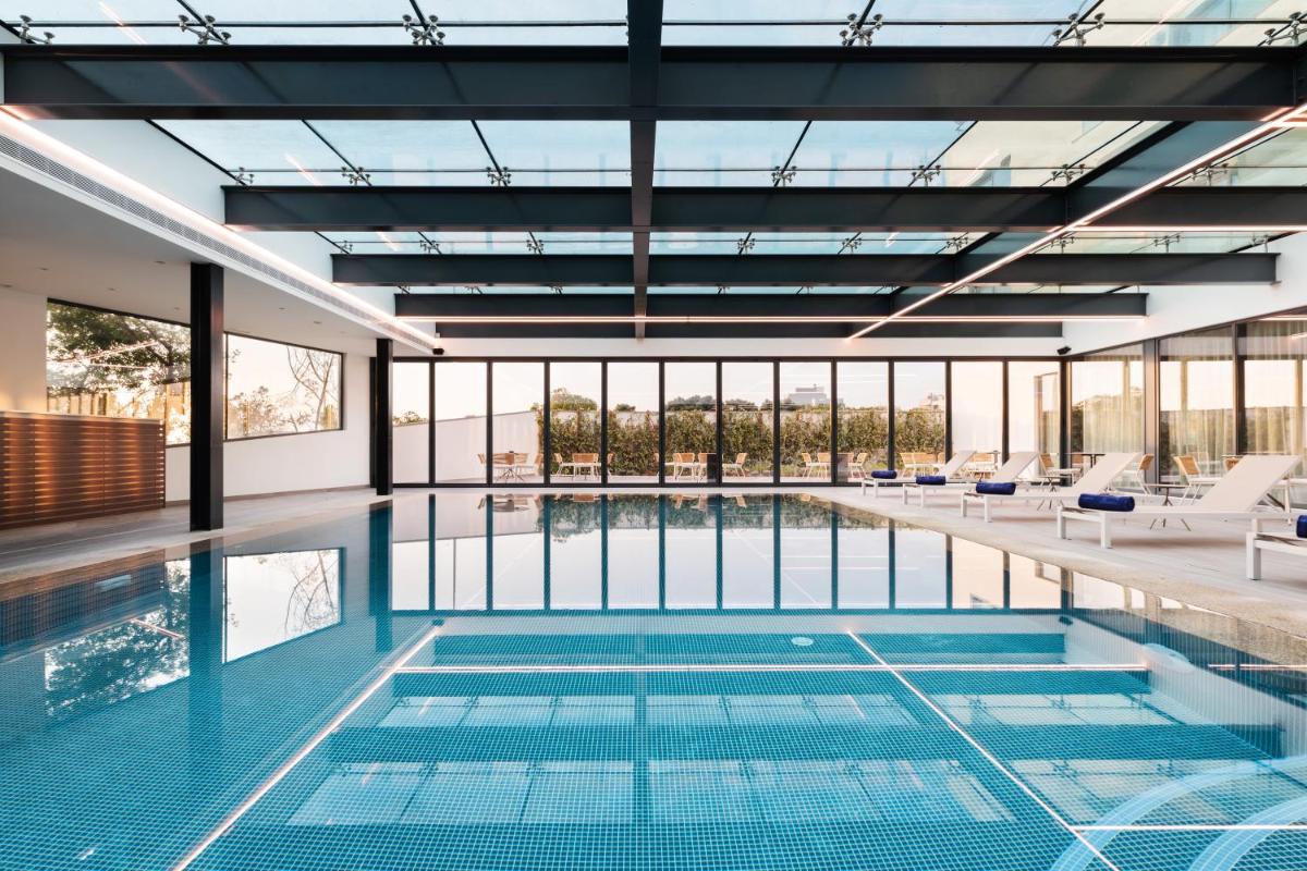uma piscina interior com cadeiras e uma grande parede de vidro em Eurostars Matosinhos em Matosinhos