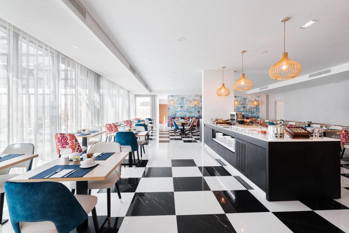 um restaurante com piso em xadrez, mesas e cadeiras em Eurostars Matosinhos em Matosinhos