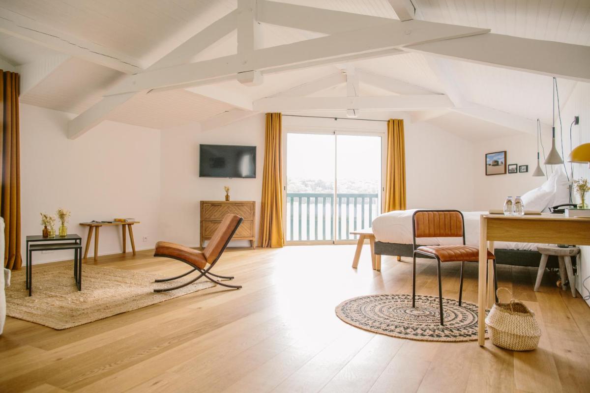 un grand salon avec un lit et un bureau dans l'établissement Les Hortensias du Lac - Fontenille Collection, à Hossegor