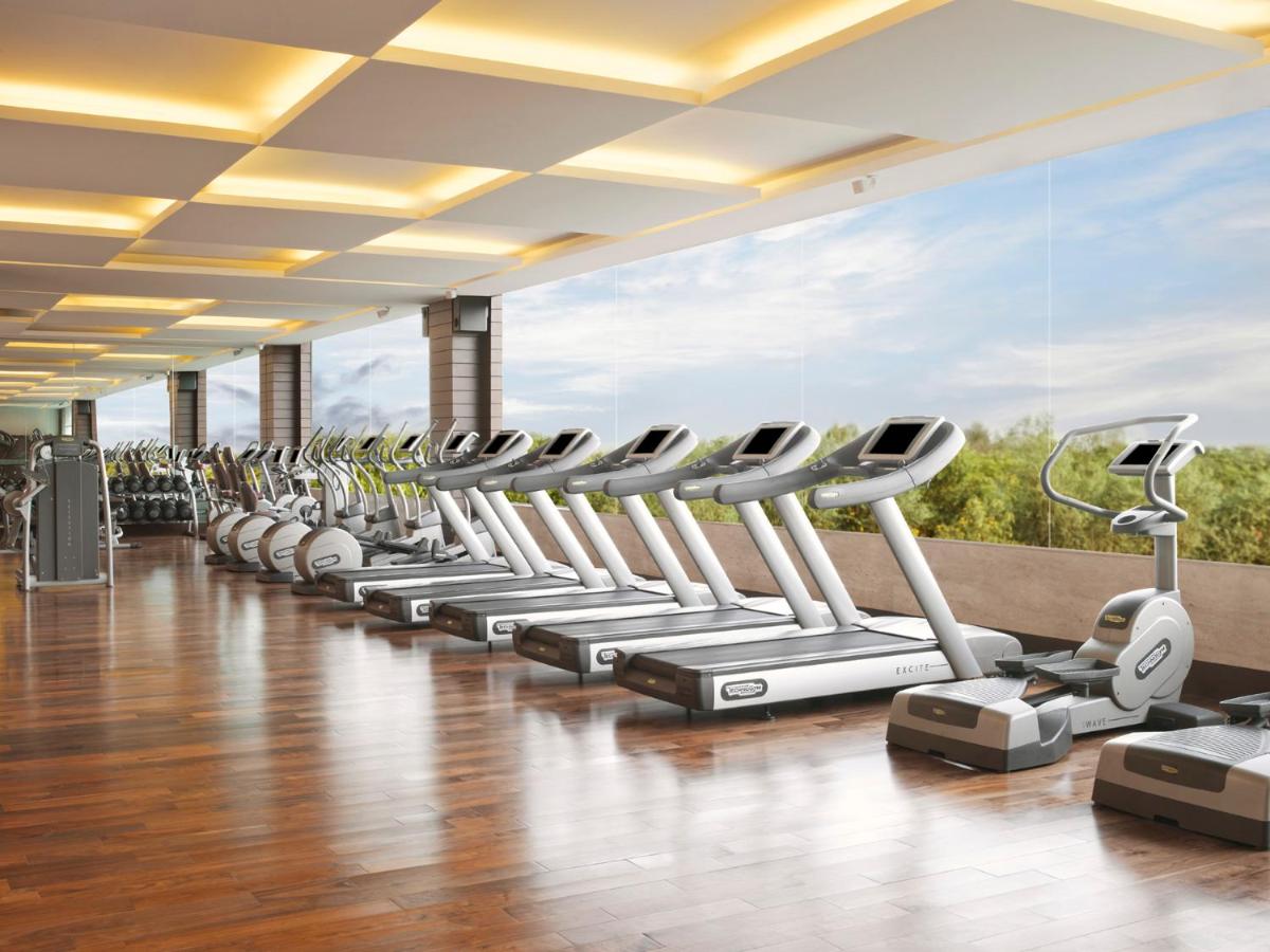 a row of exercise machines in a fitness room at The Leela Ambience Gurugram Hotel & Residences - The Luxury Urban Sanctuary in Gurgaon