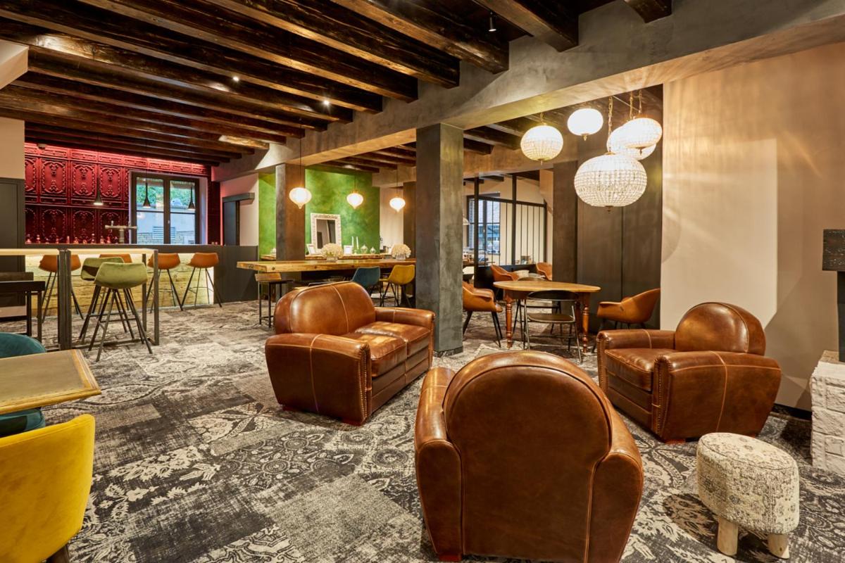 un hall d'entrée avec des chaises et des tables en cuir et un bar dans l'établissement Hôtel-SPA Le Moulin De La Wantzenau - Strasbourg Nord, à La Wantzenau